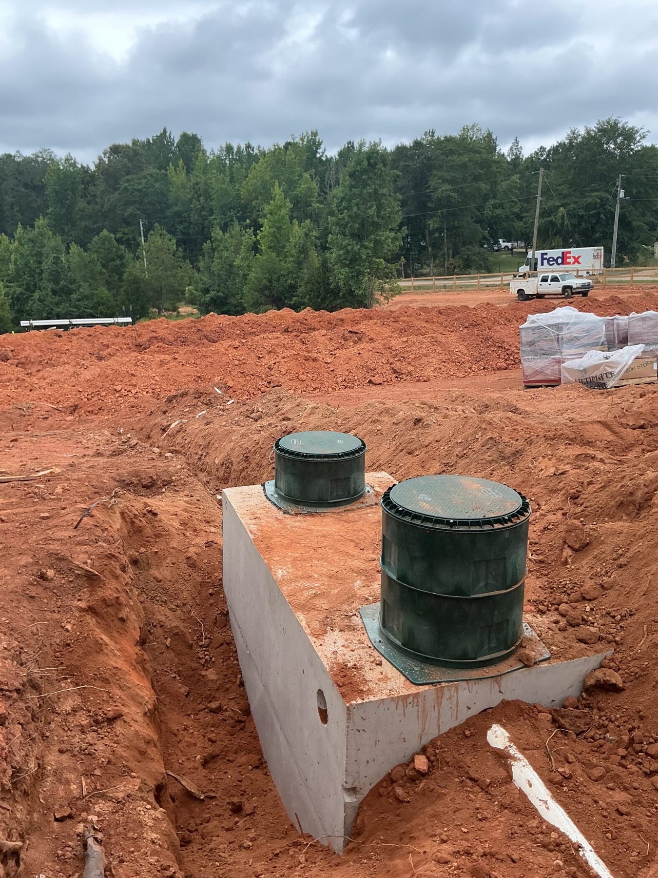 A concrete septic tank set with two green risers at a new build.