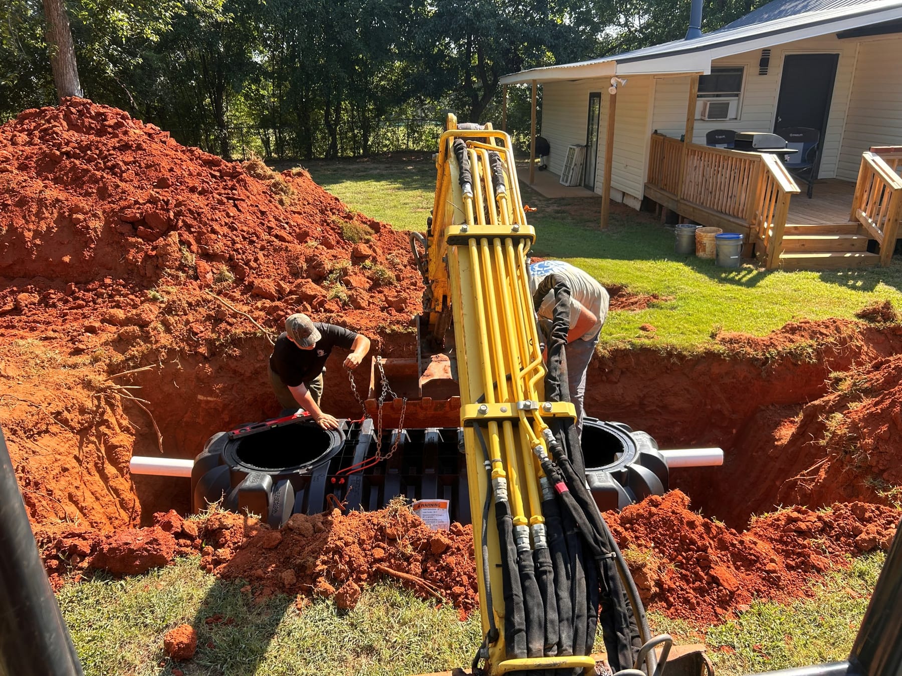 A septic tank being lowered into an open excavation on a Gray Court-area property.