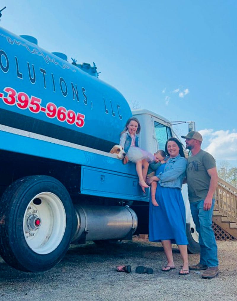 The Hometown Septic Solutions family in front of the company's pump truck.